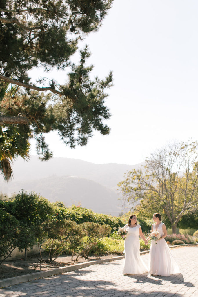LGBTQ couple walking down a path on their wedding day with scenic mountains in the background