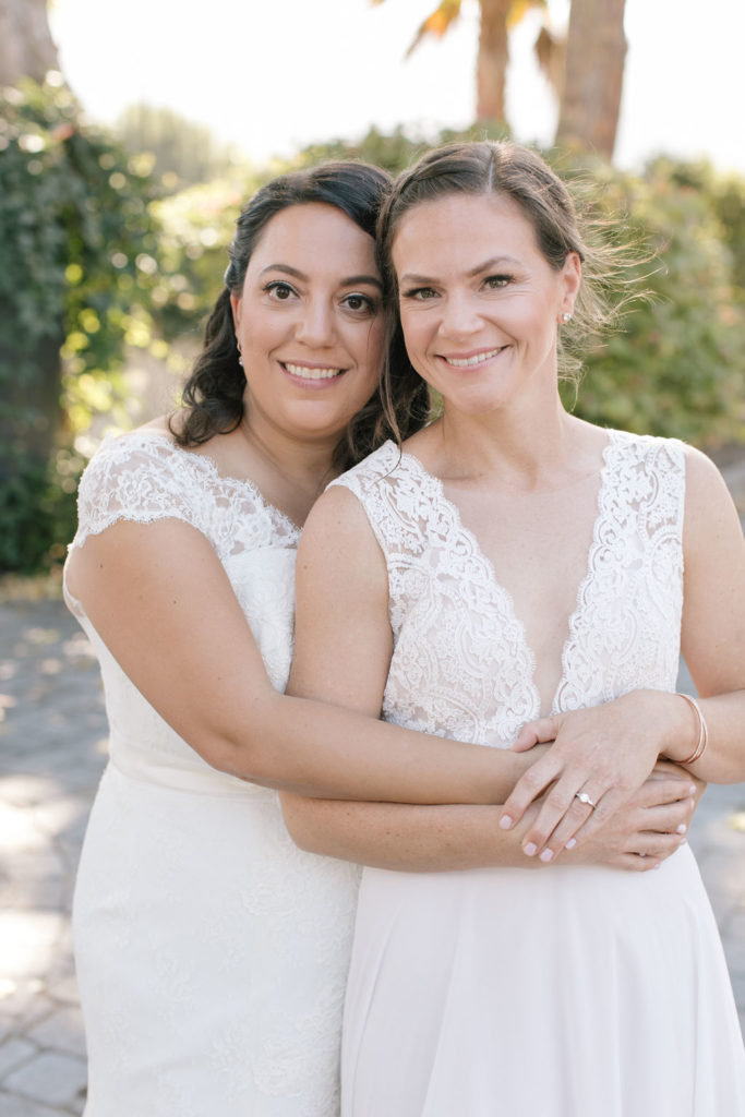 two beautiful brides embracing on their wedding day 