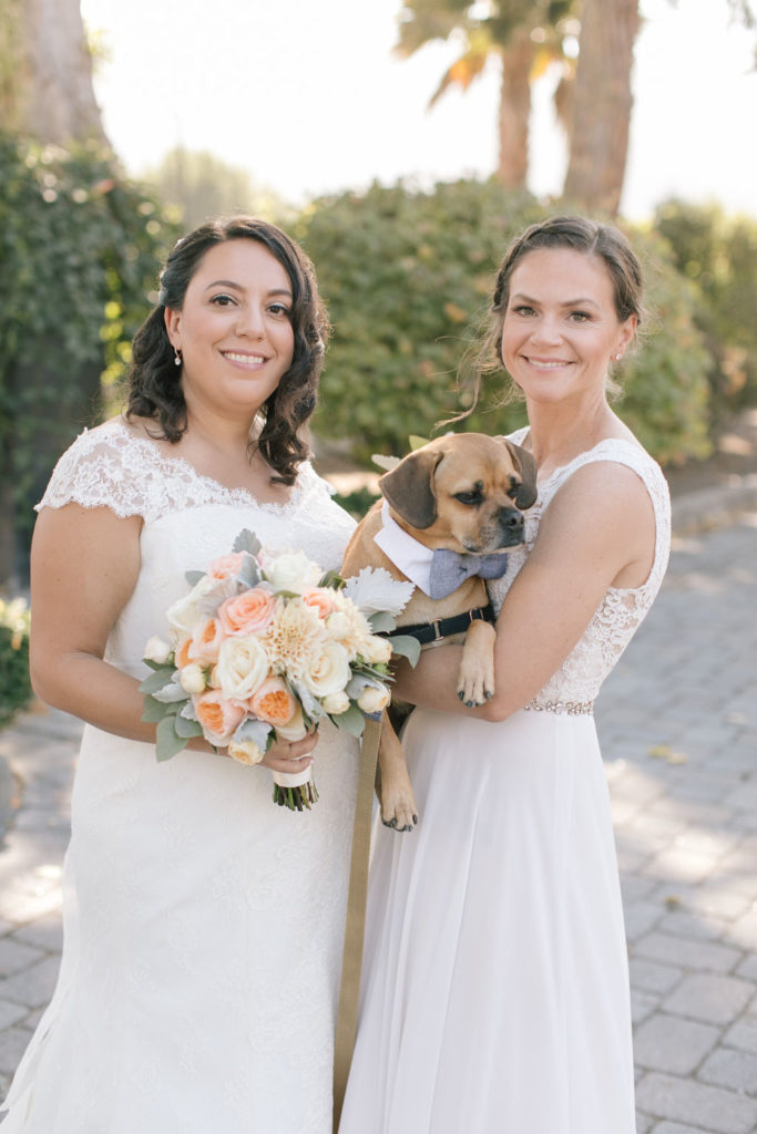 Two LGBTQ brides holding their sweet dog for a wedding photo