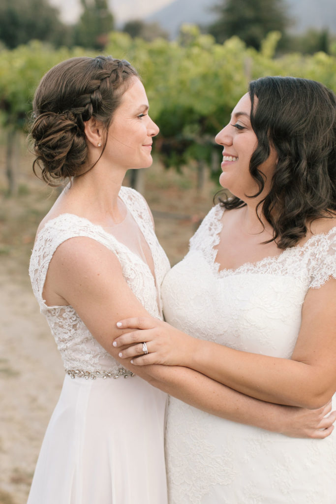 two brides embracing in the vineyard at sunset