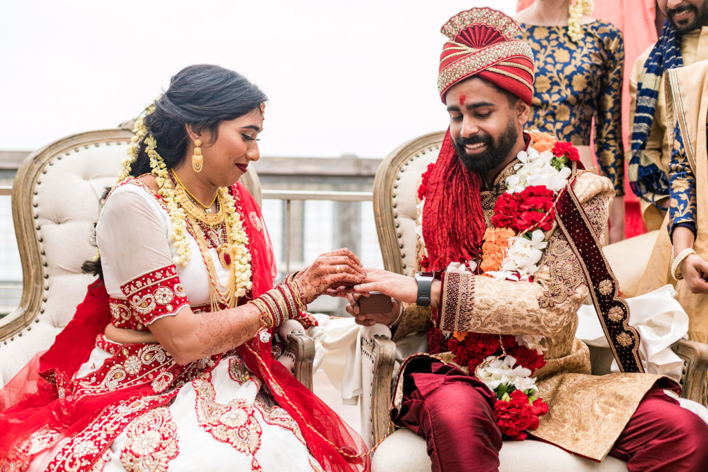 Indian bride and groom dressed in traditional north indian desi wedding clothing and exchanging rings