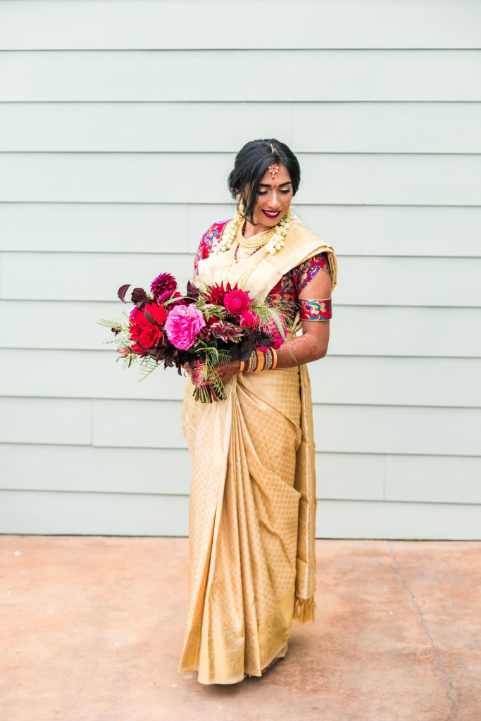 Indian bride in wedding sari holding a large bouquet of colorful flowers