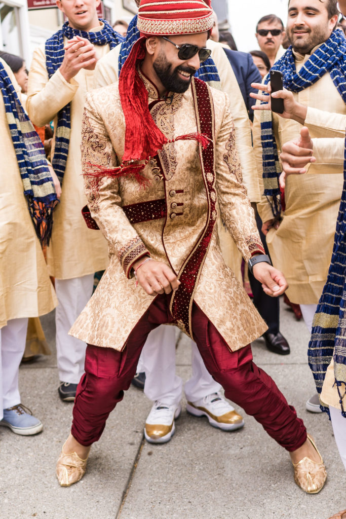 Indian groom dancing at the Baraat with friend and family 