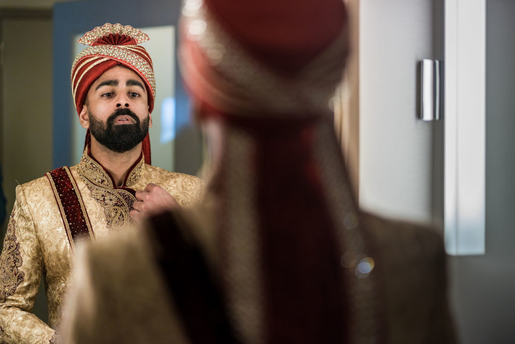 Indian groom in traditional north indian turban getting dressed for ceremony