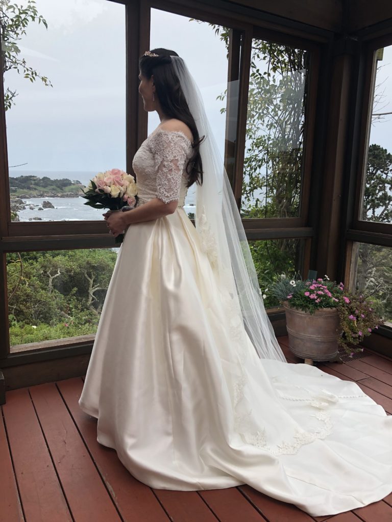 Bride looking out window over the big sur coast line 