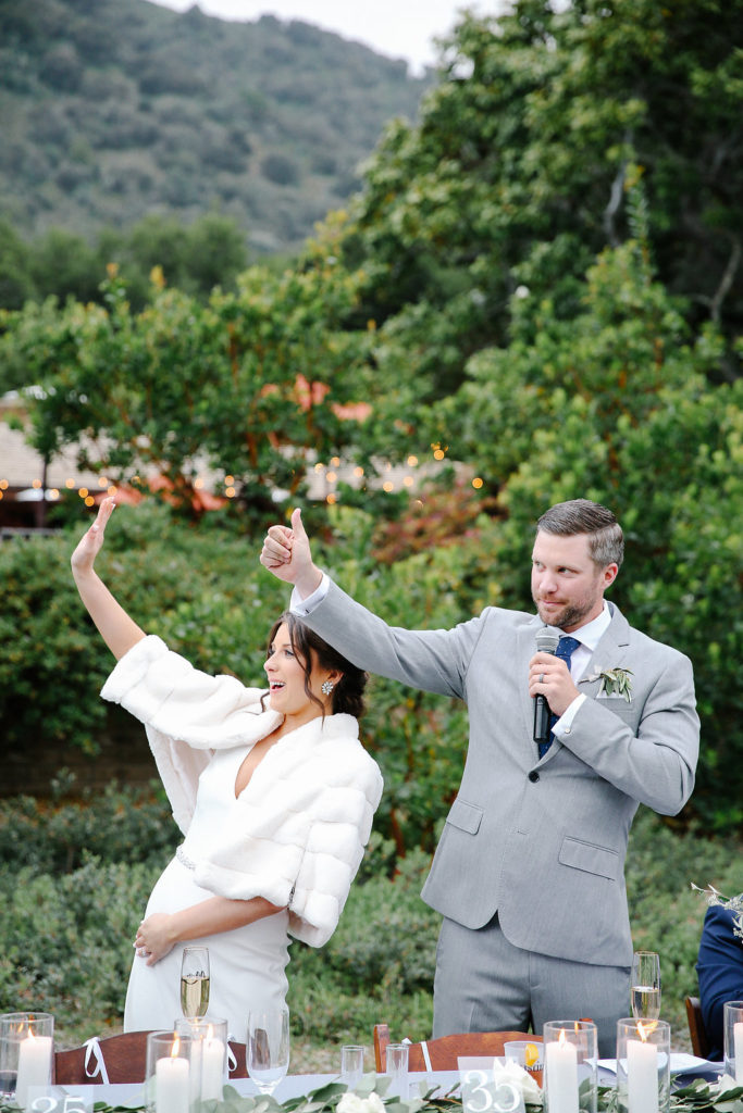 Couple waiving at guests during a thank you toast at their wedding at Gardener Ranch