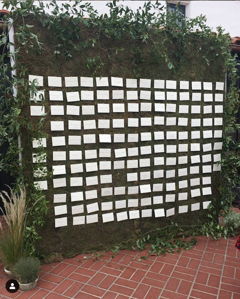 Escort cards hanging on a greenery wall
