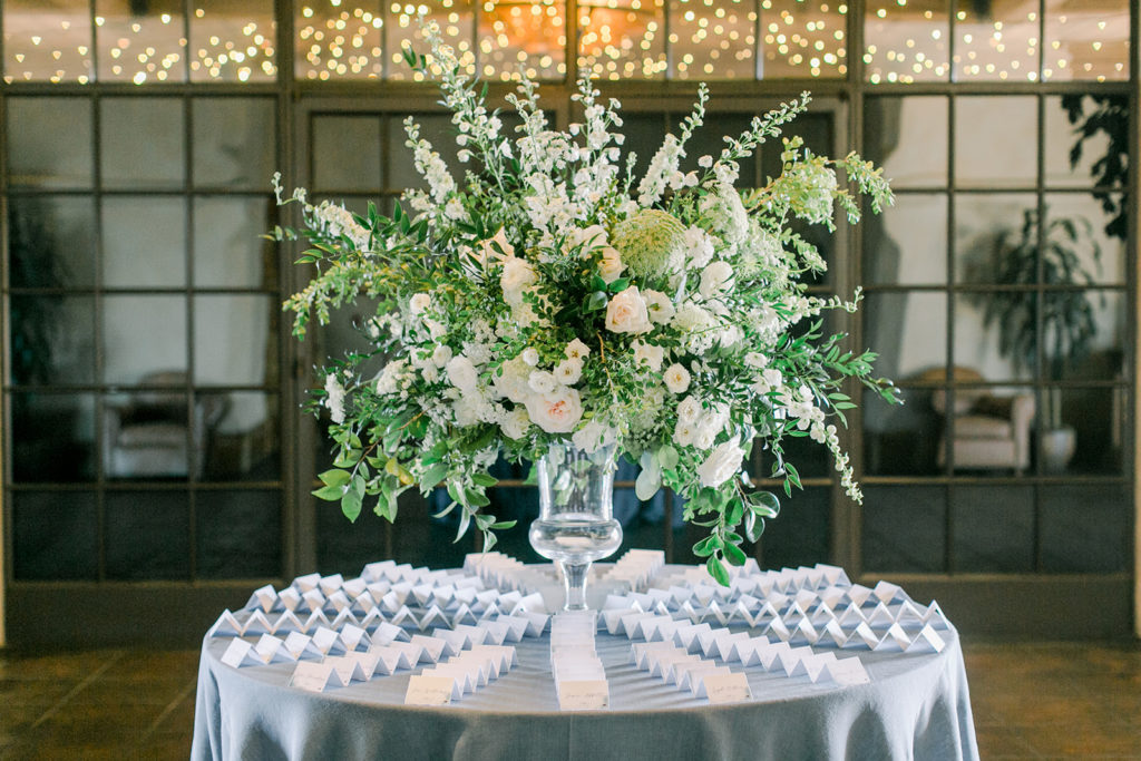 escort cards on a round table with large floral arrangement