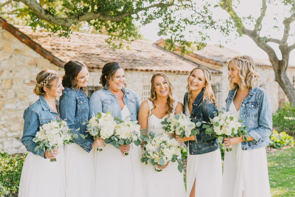 bridal party in long white dresses with denim jackets