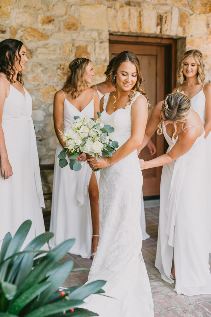 Bridesmaids in long white dresses helping the bride get ready