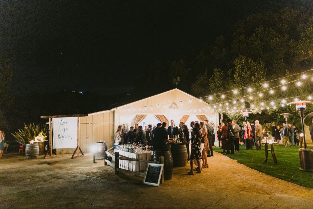  Wedding Guests lingering around the bar during the reception outside the Carriage house at Holman Ranch