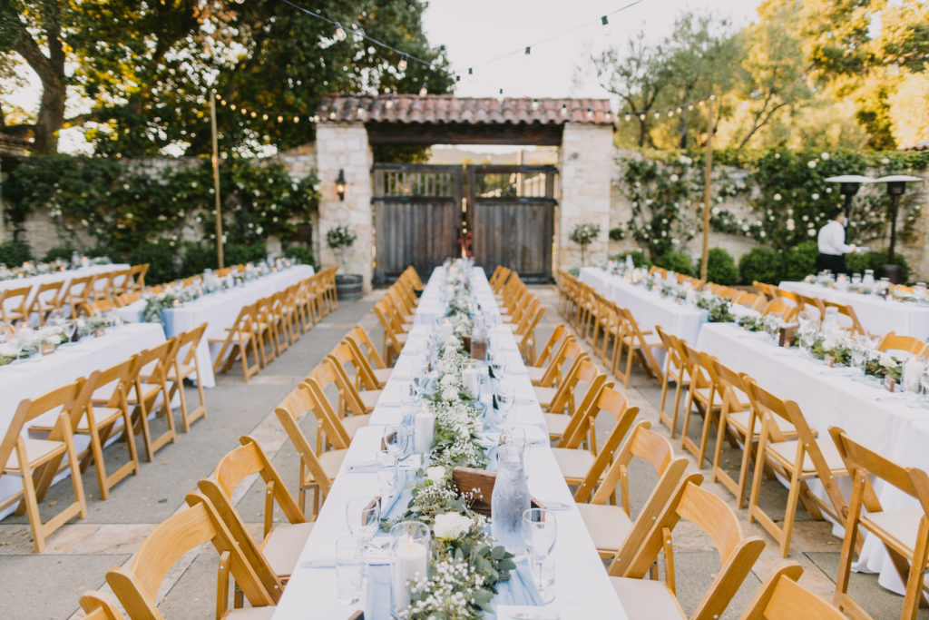 Long banquet table with ivory linen and dusty blue runner with eucalyptus garland down the center. 