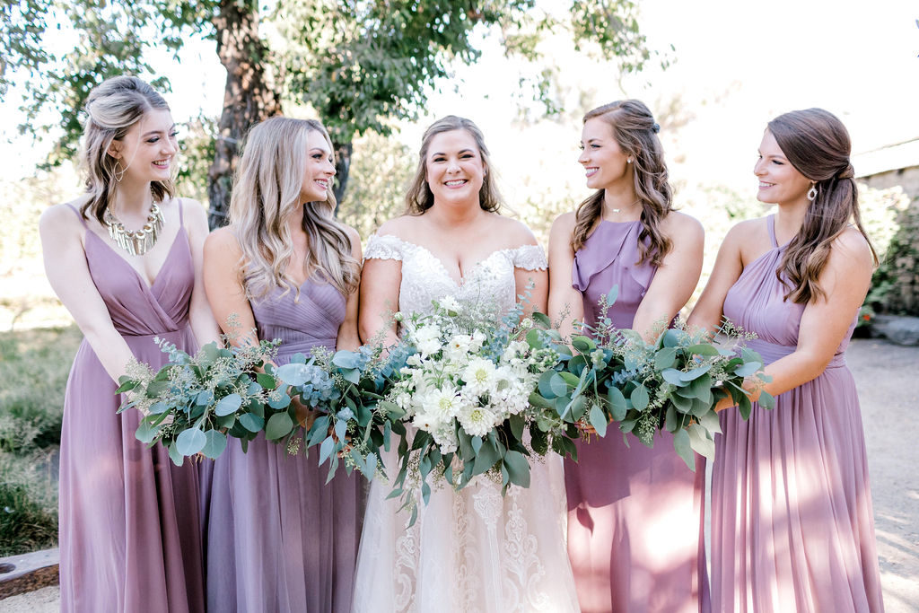 Bride with large classic white bouquet surrounded by 4 bridesmaids in Mauve long dresses with bouquets of eucalyptus and other greenery. 
