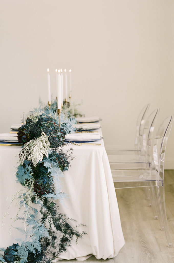 White velvet table with blue garland and candles