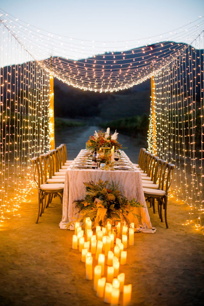 Night time image of tables in the vines with a canopy of twinkle lights