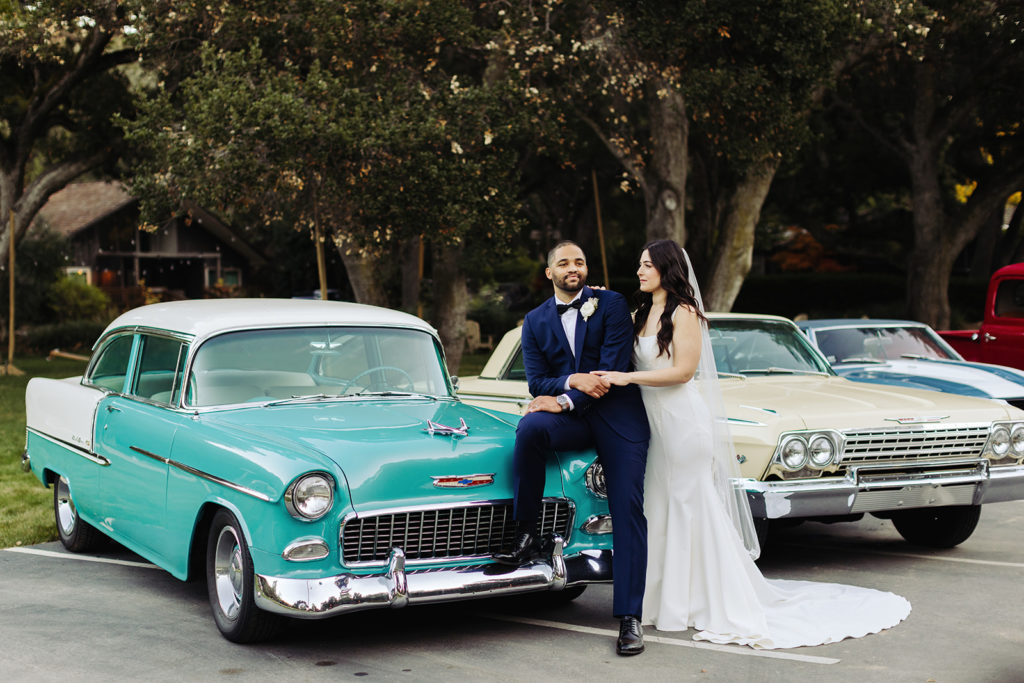 Bride and Groom Posing on Classic Car