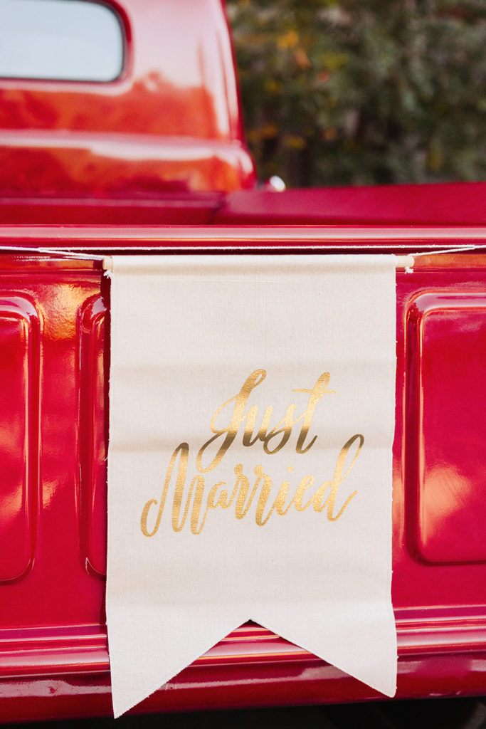 Vintage red truck with Just Married banner hung on tailgate