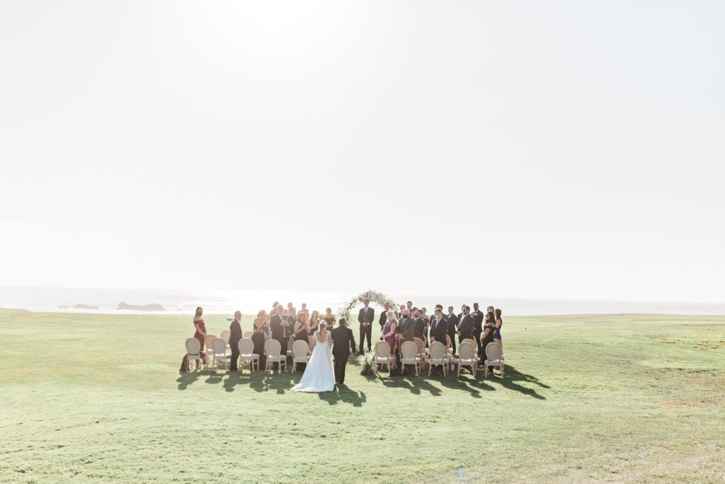 Bride walking down the aisle during the ceremony on a waterfront golf course